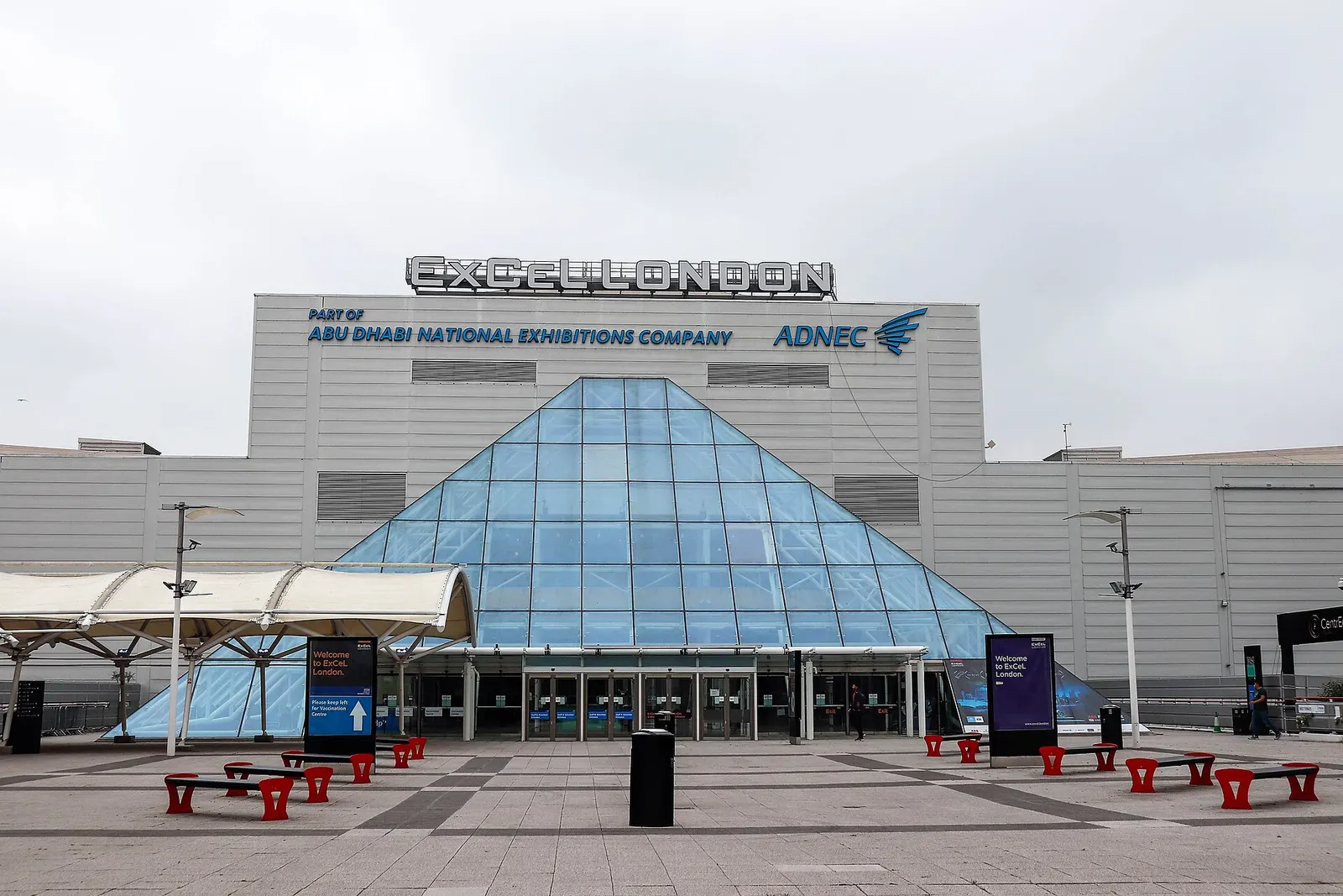 The glass pyramid main entrance of ExCeL London beneath its rooftop name sign