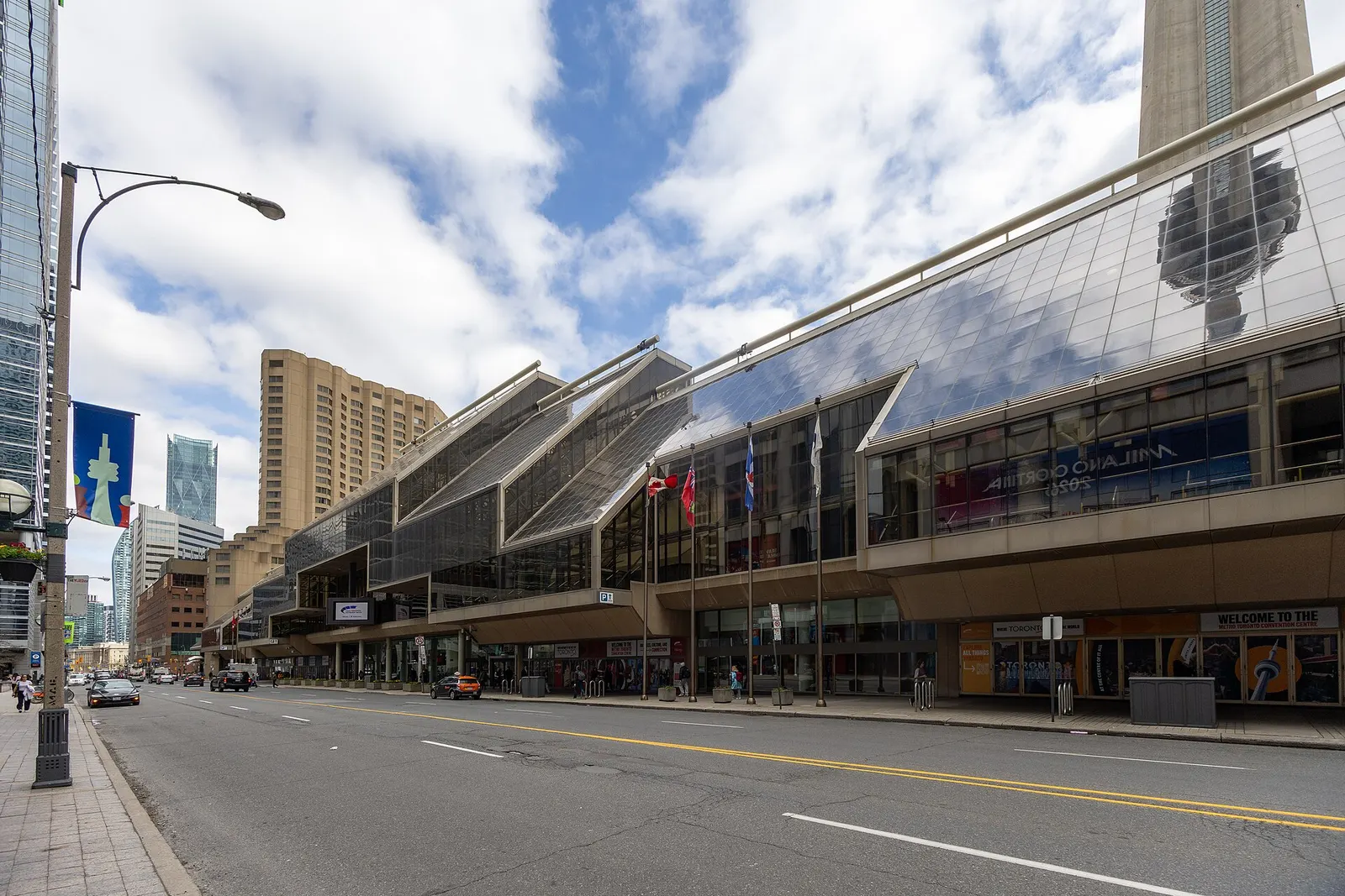 The glass North Building of the Metro Toronto Convention Centre along Front Street, with the CN Tower reflected