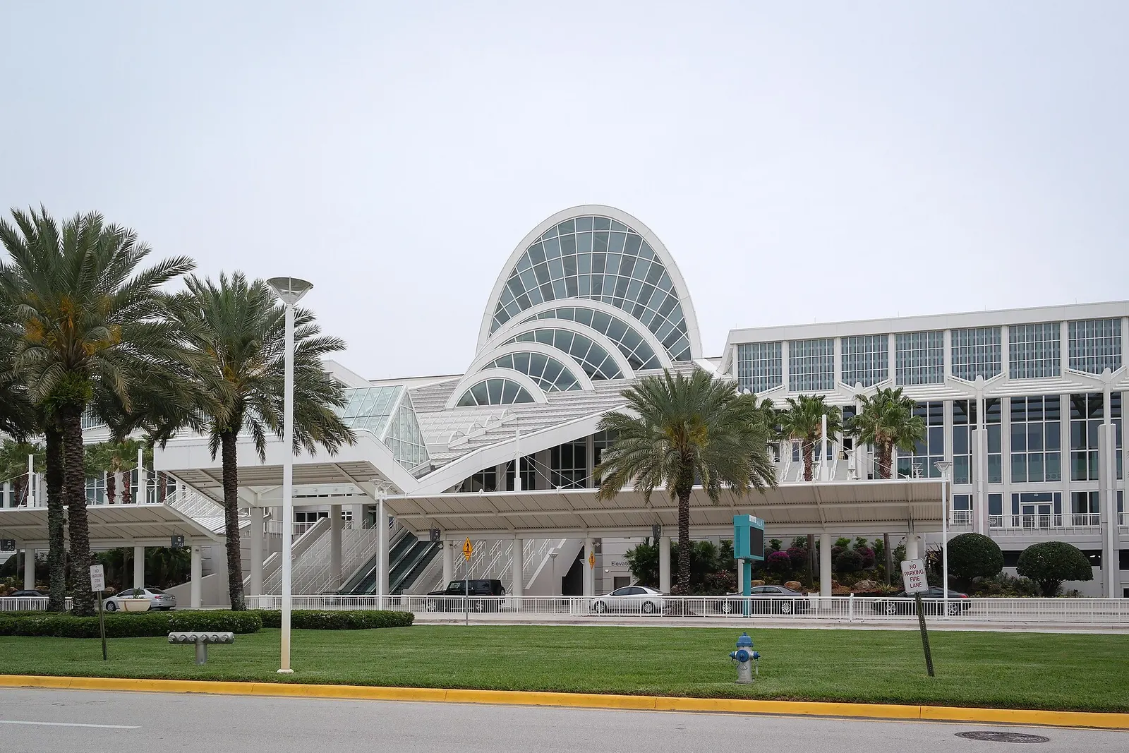 The arched glass entrance of the Orange County Convention Center's West Building behind palm trees